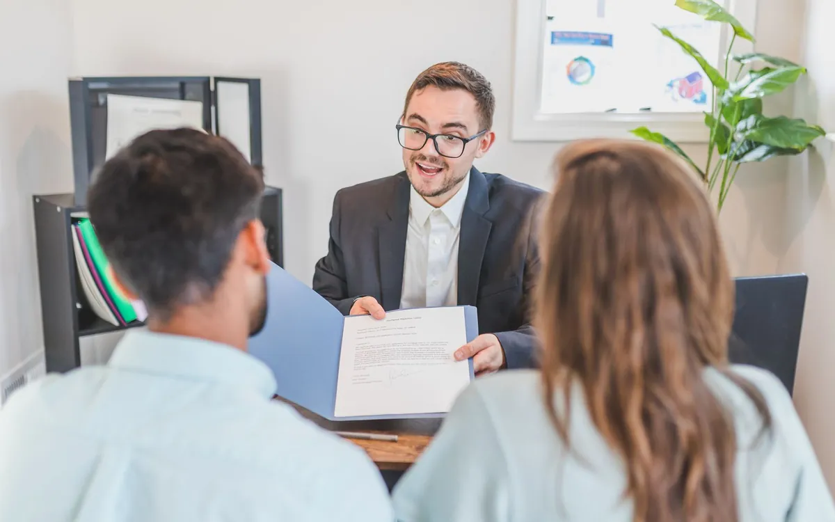 Consultor explicando o contrato de crédito a um casal antes da assinatura